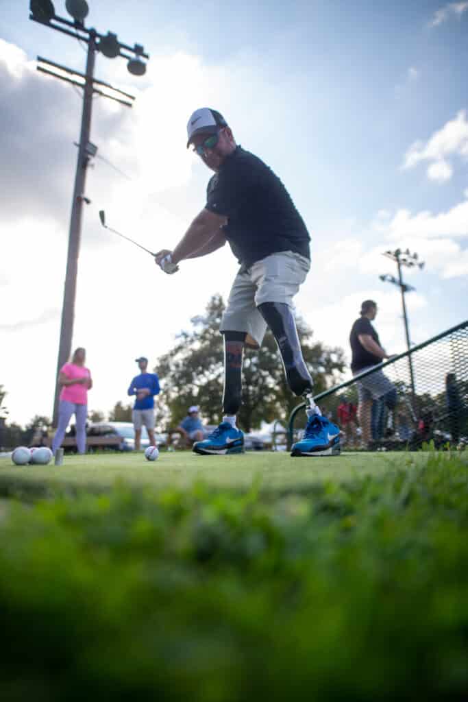 Man golfing with leg prosthetics 